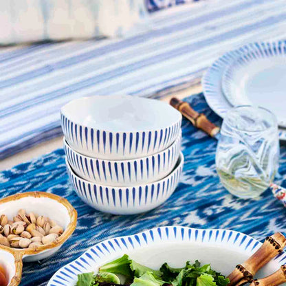 stack of Sitio Stripe Delft Blue cereal bowls on a set dining table