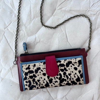 rectanglar dark red wallet with black and white spotted animal print pocket with chain strap on it.