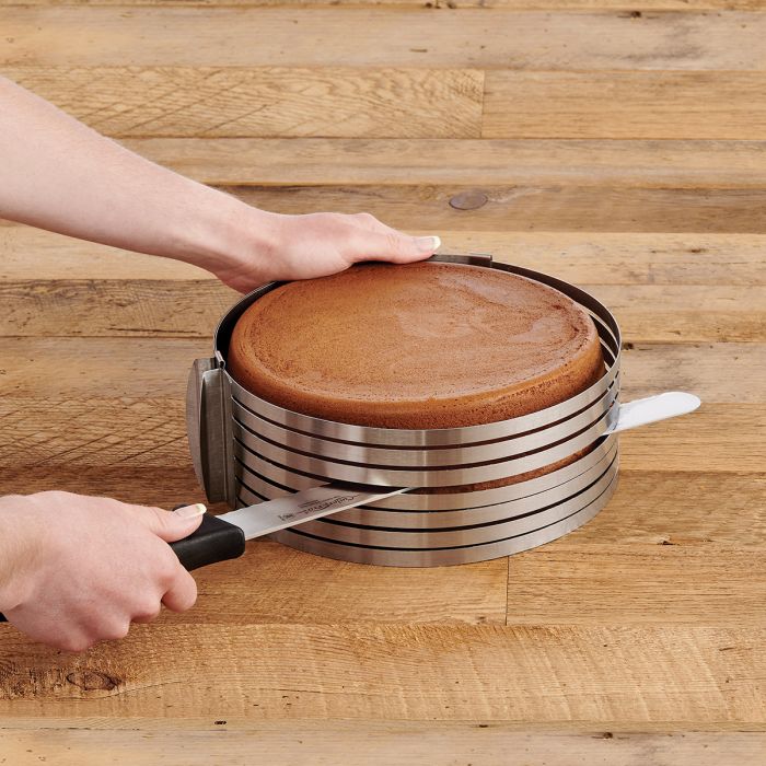 hand holding knife and slicing a round cake in cake slicer