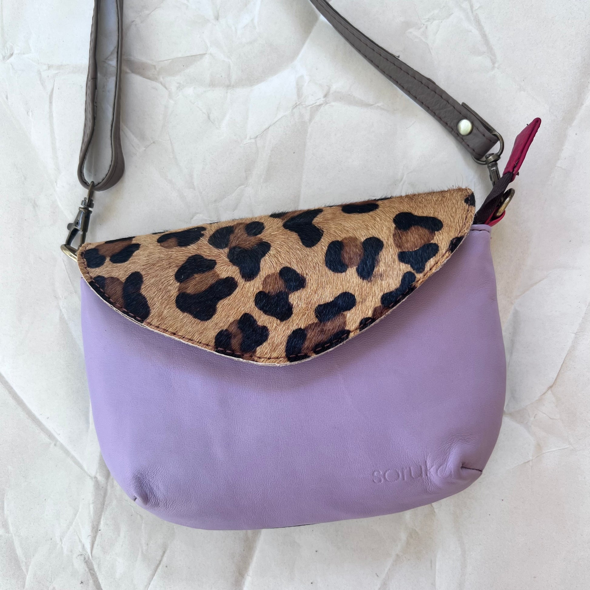 small lavender carol bag with cheetah print flap and grey shoulder strap.