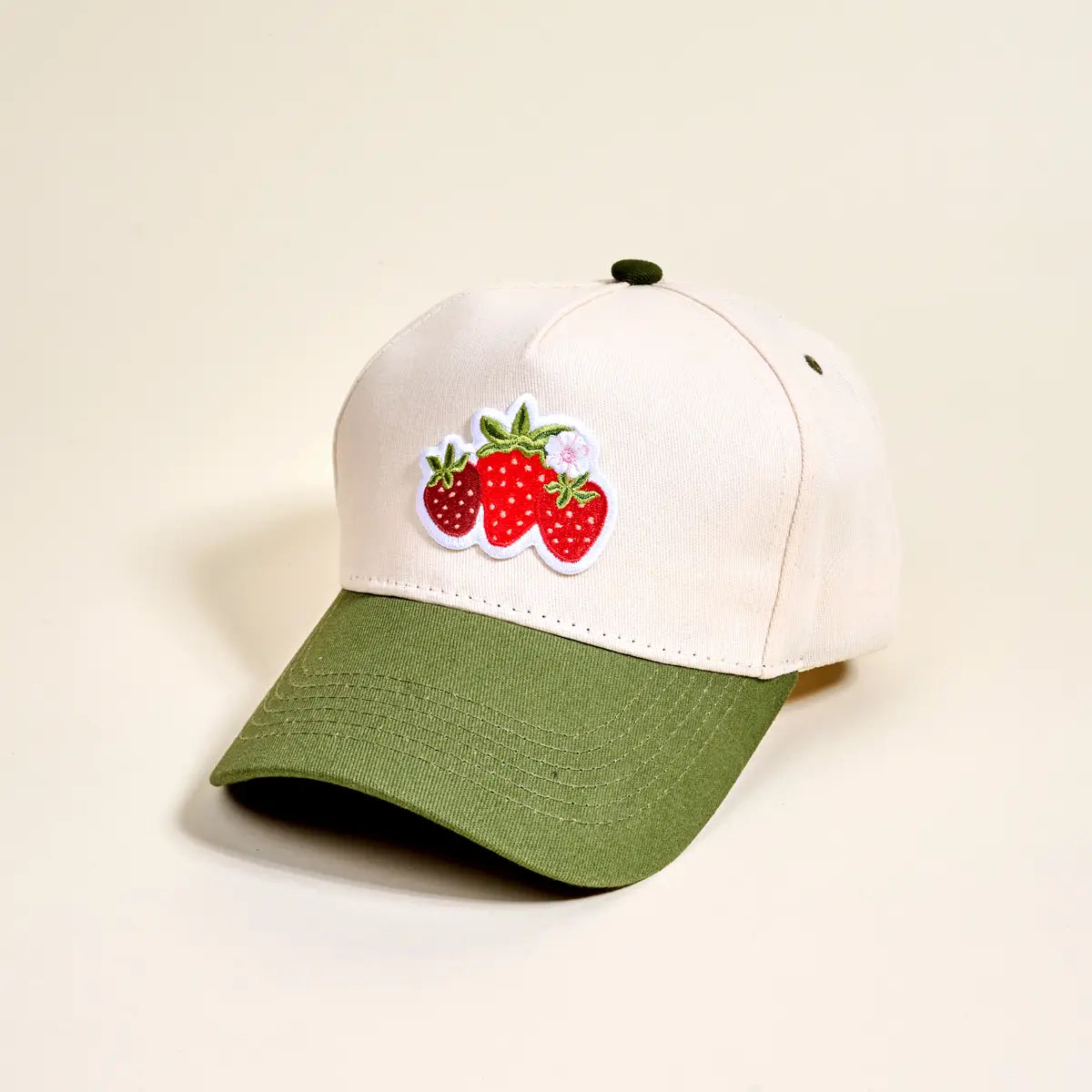 White and green cap with strawberry design on a beige background