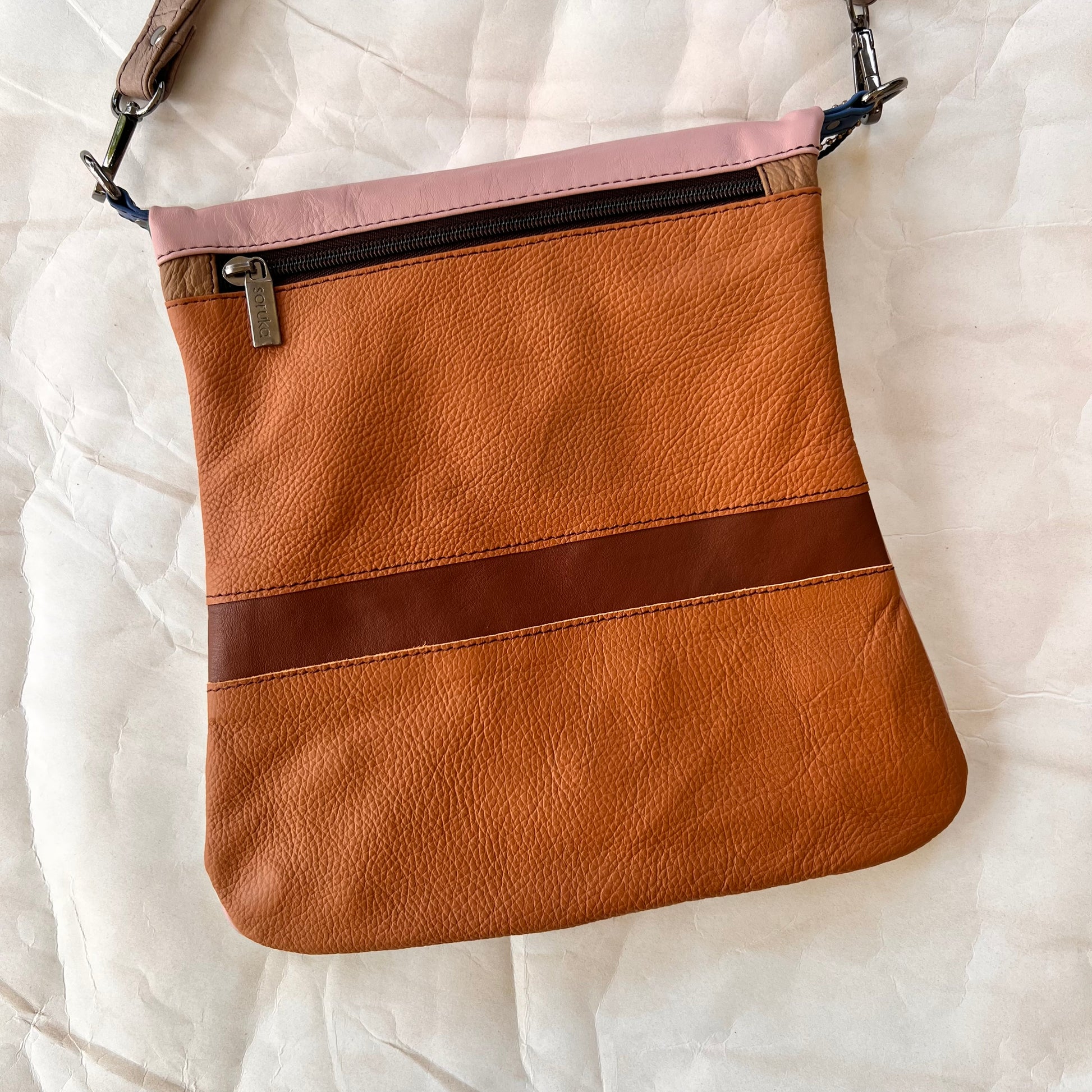 shades of brown striped greta bag with zipper across the top.
