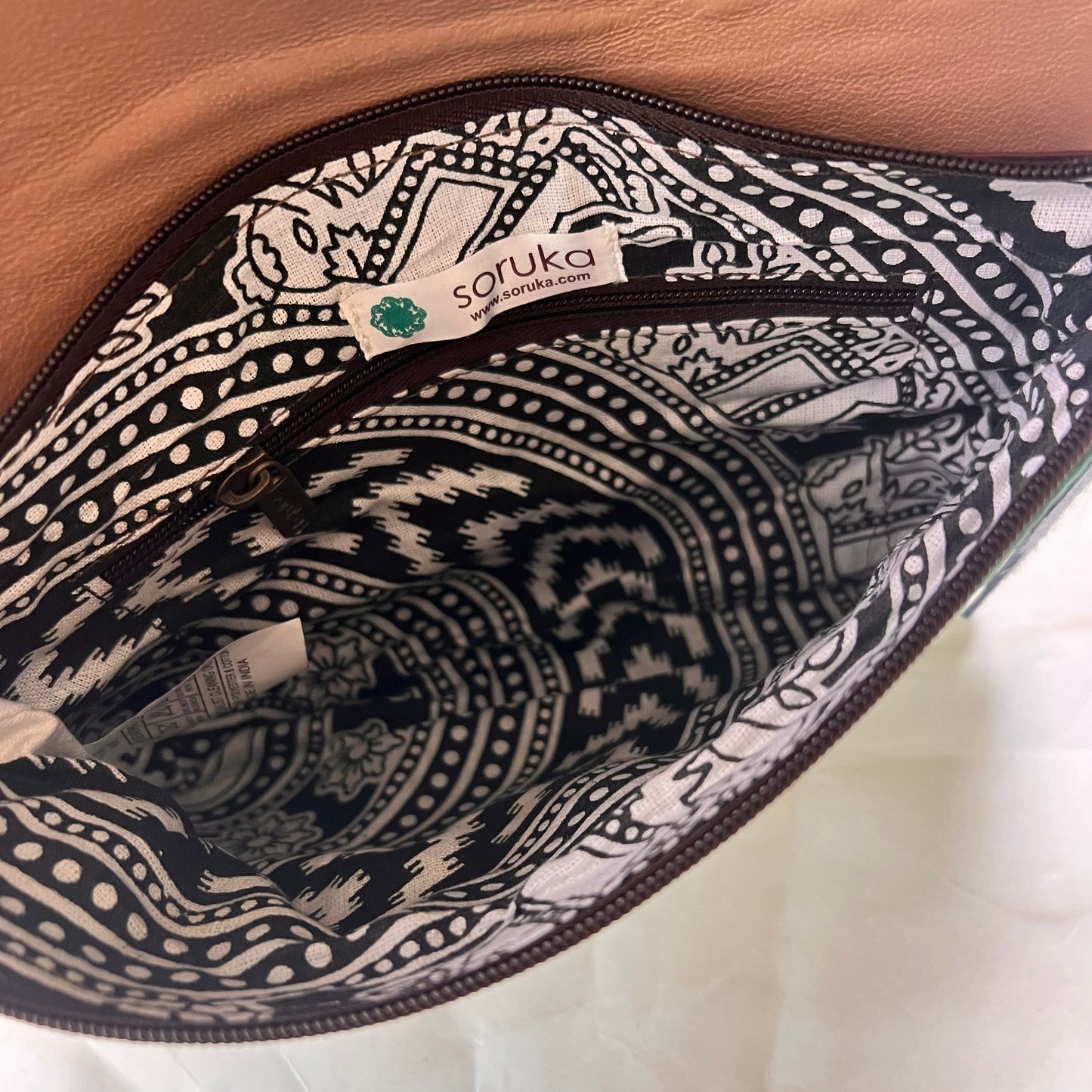 interior view of saddle bag showing inner zip pocket and patterned lining.