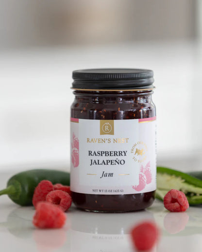jar of Raspberry Jalapeno Jam arranged with raspberries and jalapeno peepers.