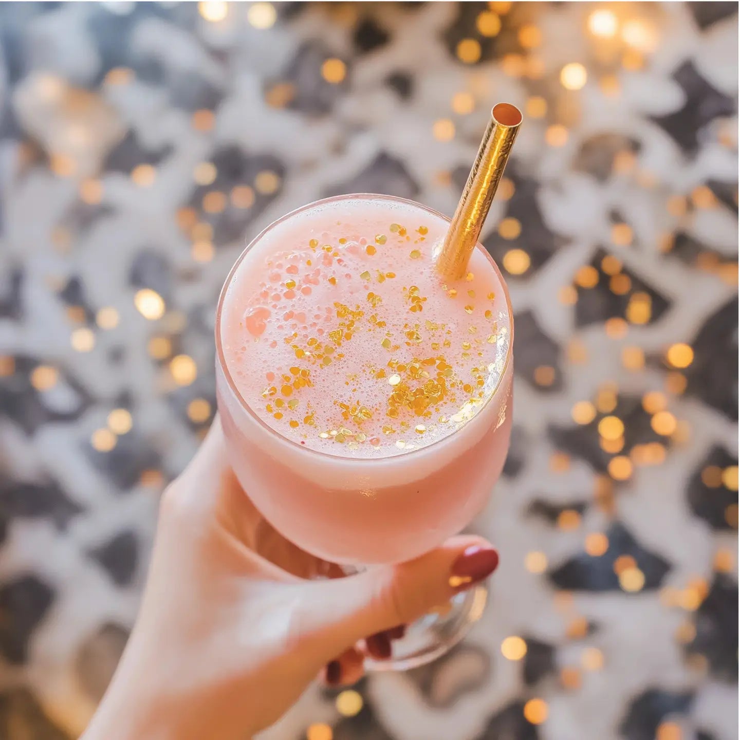 wind holding a pink drink with gold glitter on top