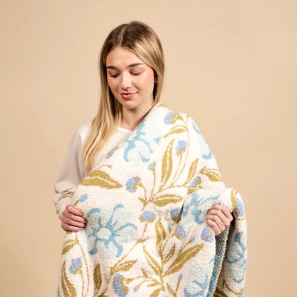 person holding a floral-patterned blanket against a beige background
