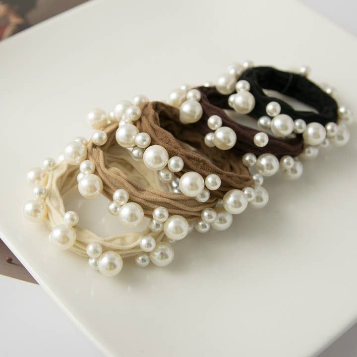 5 hair neutral colored hair ties in a row on a white tray