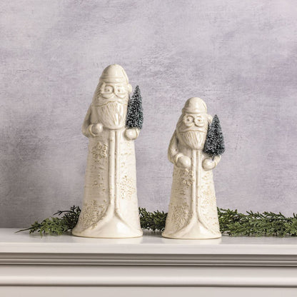 2 sizes of ceramic Santa figurines set on a mantle with greenery