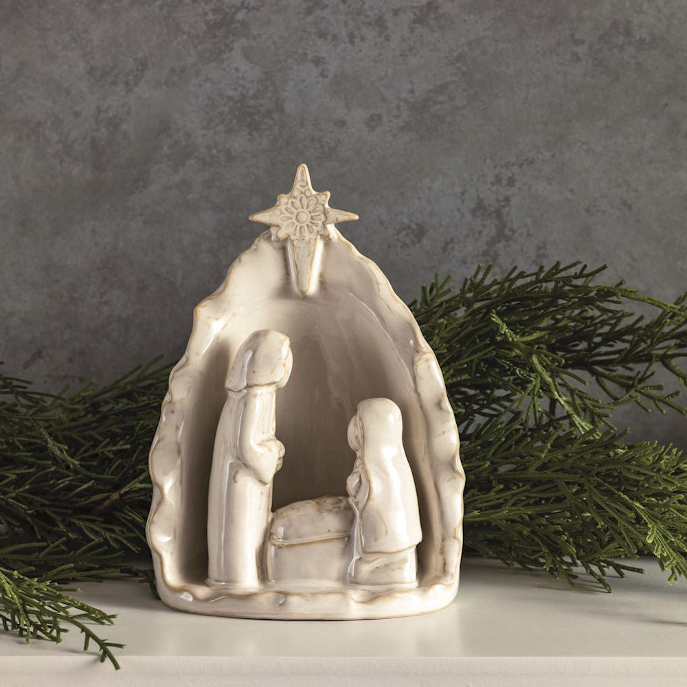 White Stoneware Nativity Set arranged with greenery on a table.