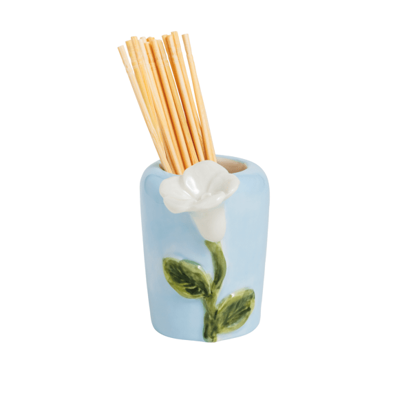 blue ceramic holder with white flower and green leaf design holding wooden toothpicks shown on a white background
