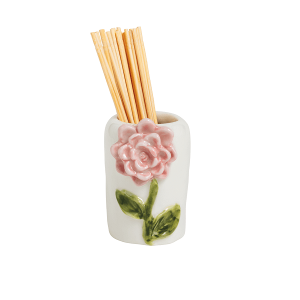 white ceramic holder with pink flower and green leaf design holding wooden toothpicks shown on a white background