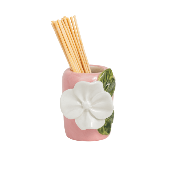 Pink ceramic holder with white flower and green leaf design holding wooden toothpicks shown on a white background
