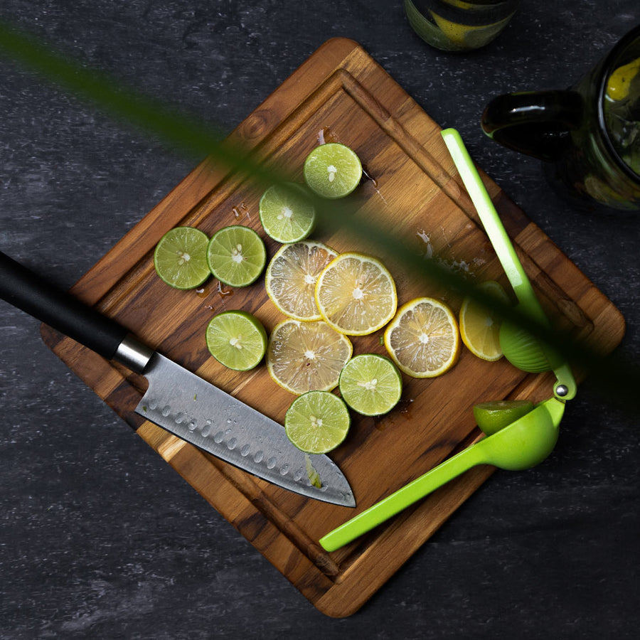 top view of board with limes, juicer, and knife on it.