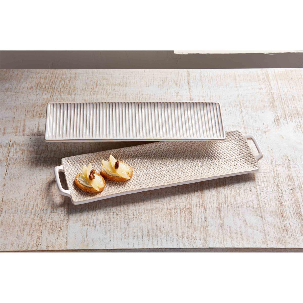 small tray with ribbed lines and large tray with handles and woven pattern arranged on a wooden table with snacks on the larger tray.