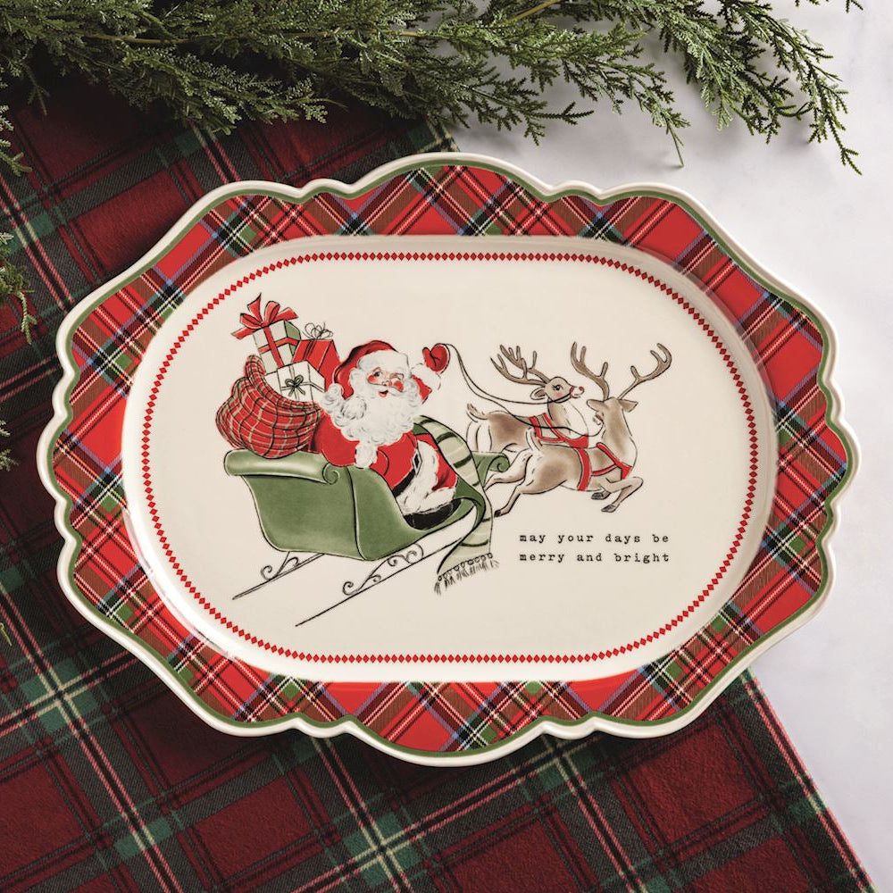 tartan platter with santa image in the center set on a tartan runner next to evergreen branches
