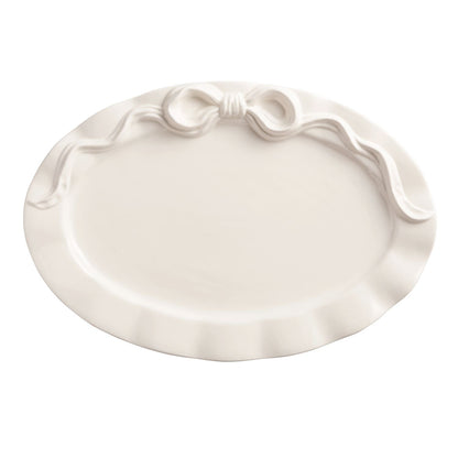 White ceramic platter with decorative bow design on a white background