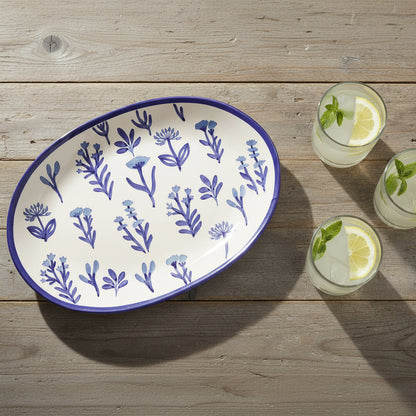 Oval ceramic platter with blue floral pattern on a wooden surface with glasses of lemonade.