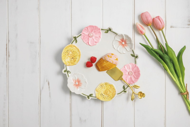 round platter with floral design around the rim with treats on it set on a wooded table with pink tulips