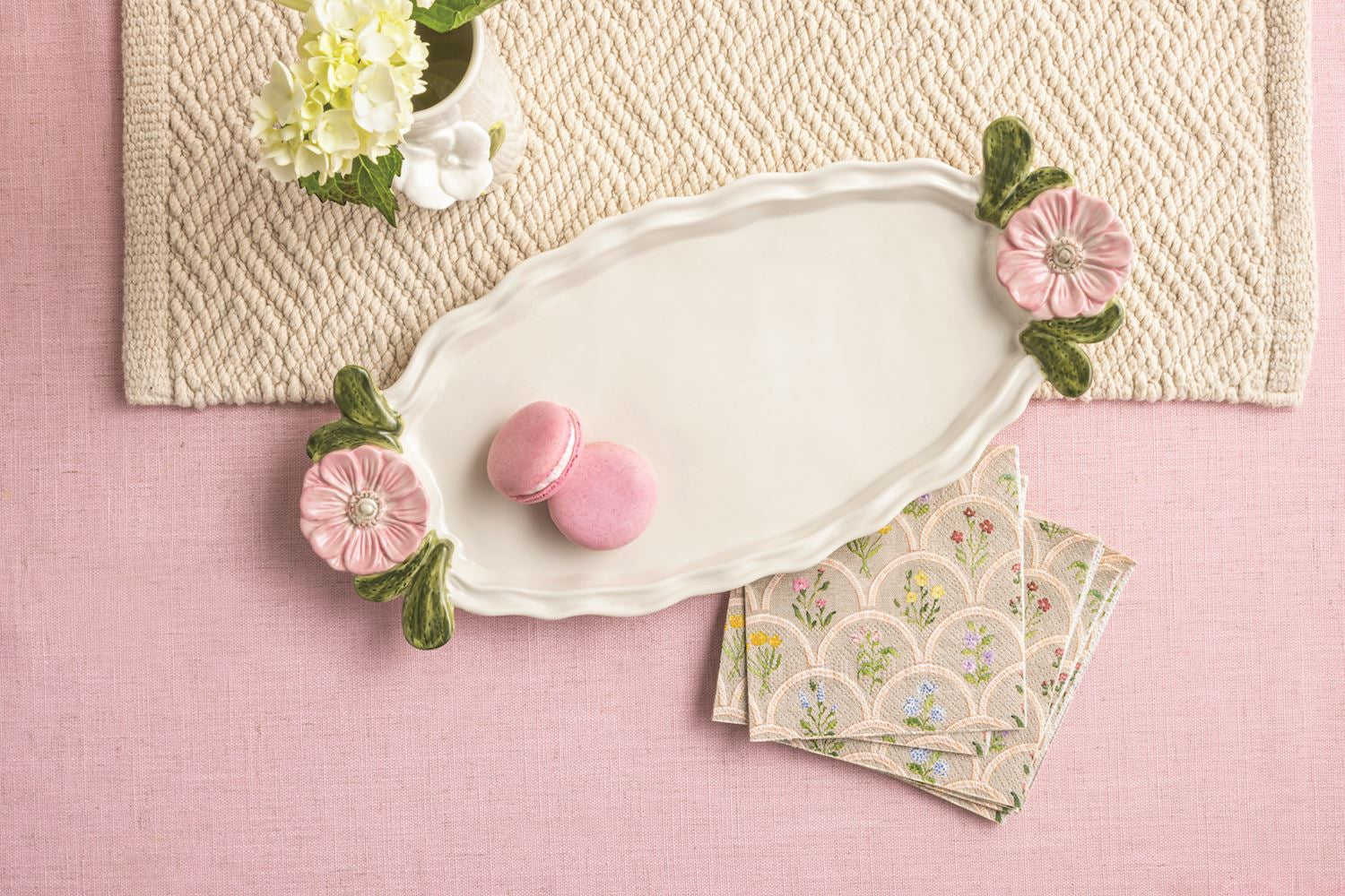 flower handle tray with pink cookie on it set on a pink surface with napkins and flowers