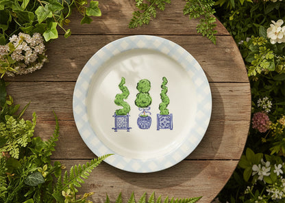 round platter with blue gingham boarder with 3 topiary drawings in the center set on a table surrounded by greenry