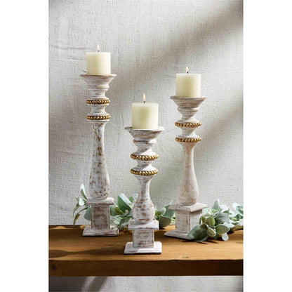 all three sizes of gold bead candlesticks displayed on a narrow hall table next to lambs ear sprigs