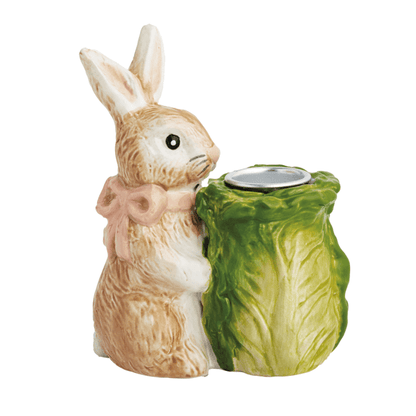 Ceramic rabbit holding a green cabbage-shaped taper holder on a white background