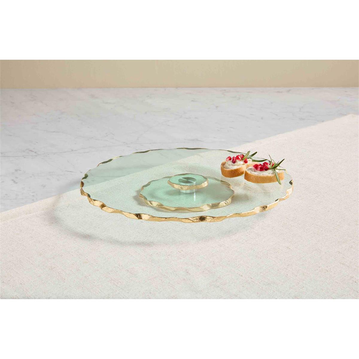 glass lazy Susan with gold rims set on a counter with slices of bread topped with berries and herbs on it.