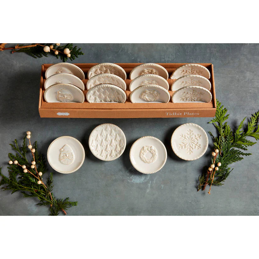 box of assorted tidbit plates and one of each style of plates arranged on a table with sprigs of greenery.