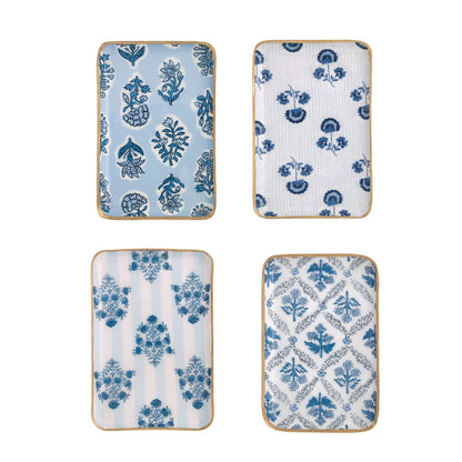Four decorative enameled trays with blue floral patterns arranged on a white background