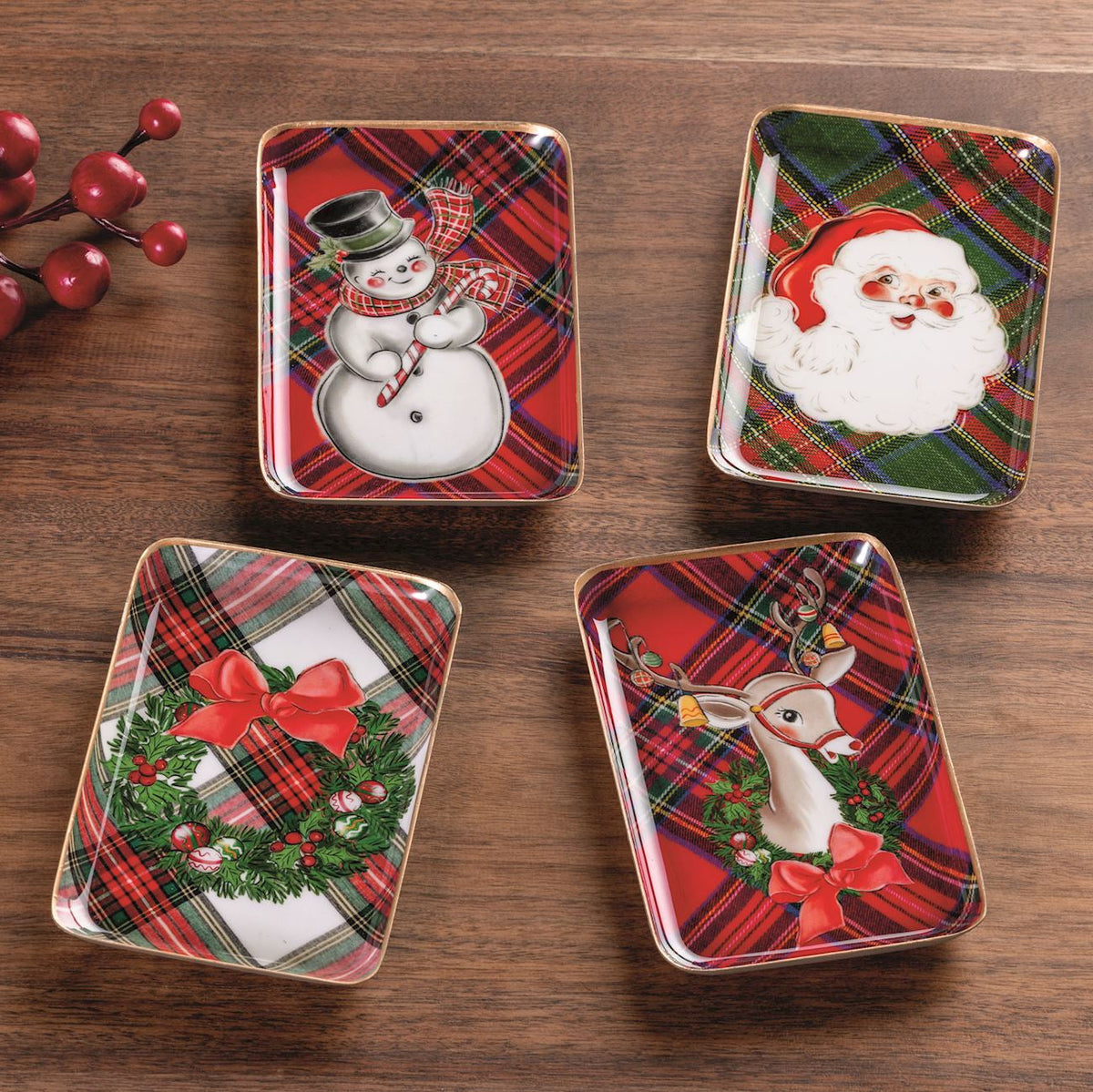 4 tartan enamel trays with holiday scenes on a wood table
