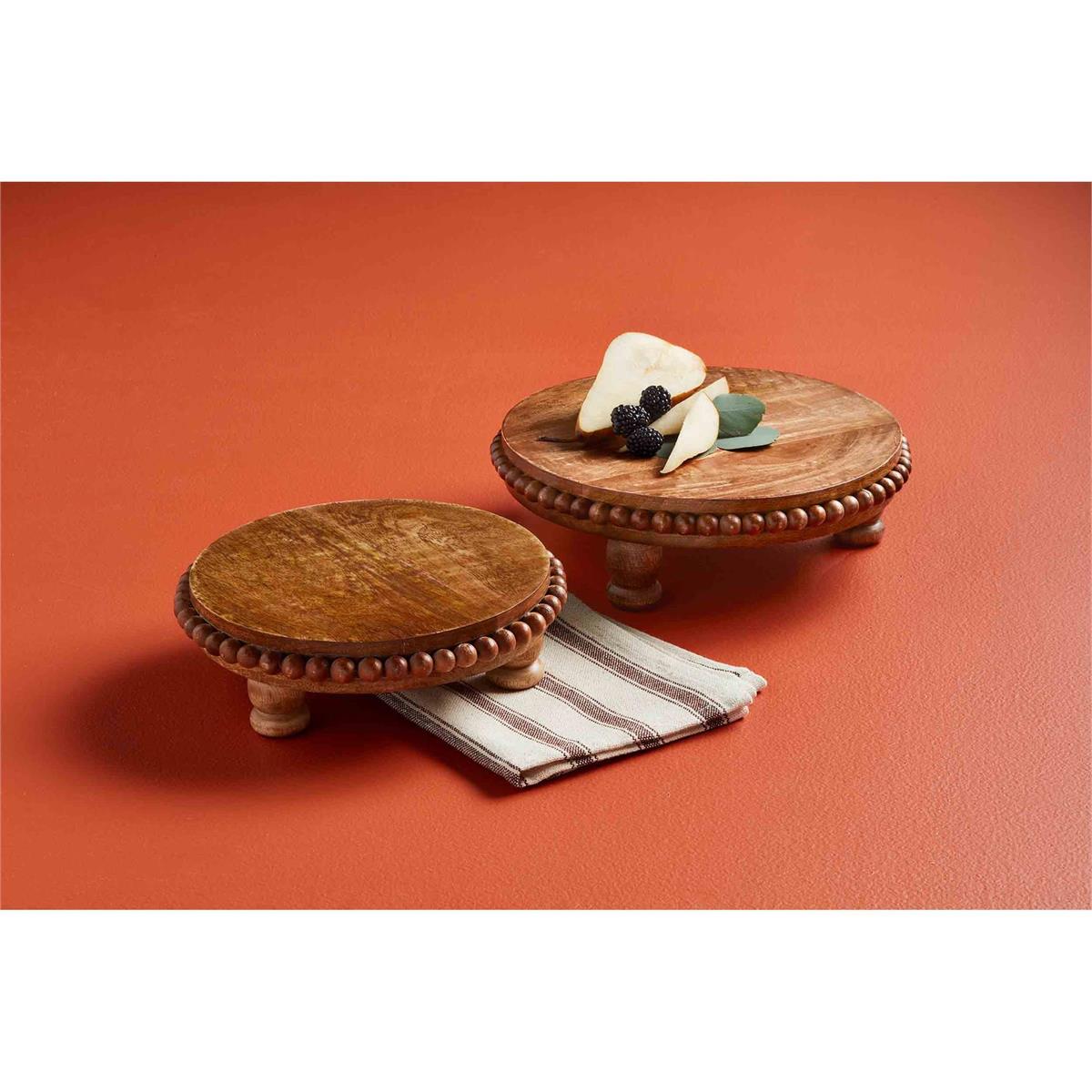 both sizes of beaded risers displayed with a towel underneath one and sliced fruit and berries on the other against a rust colored background