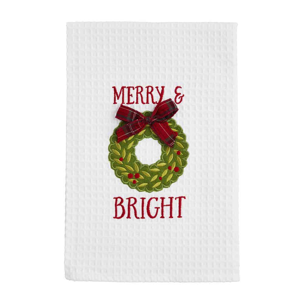 white waffle weave towel with a green wreath and "merry and bright" embroidered on it.