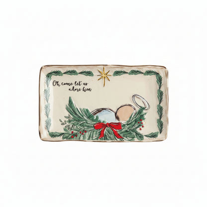 ceramic tray with evergreen boarder, baby jesus laying in an evergreen manger, and ' oh come let us adore him' in script on top left