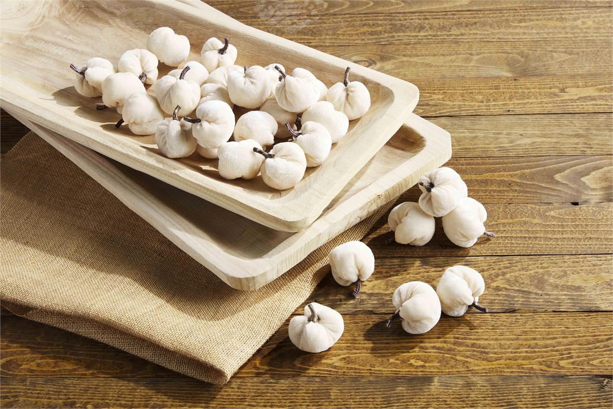 mini cream velvet pumpkins scattered on a stack of wooden trays.