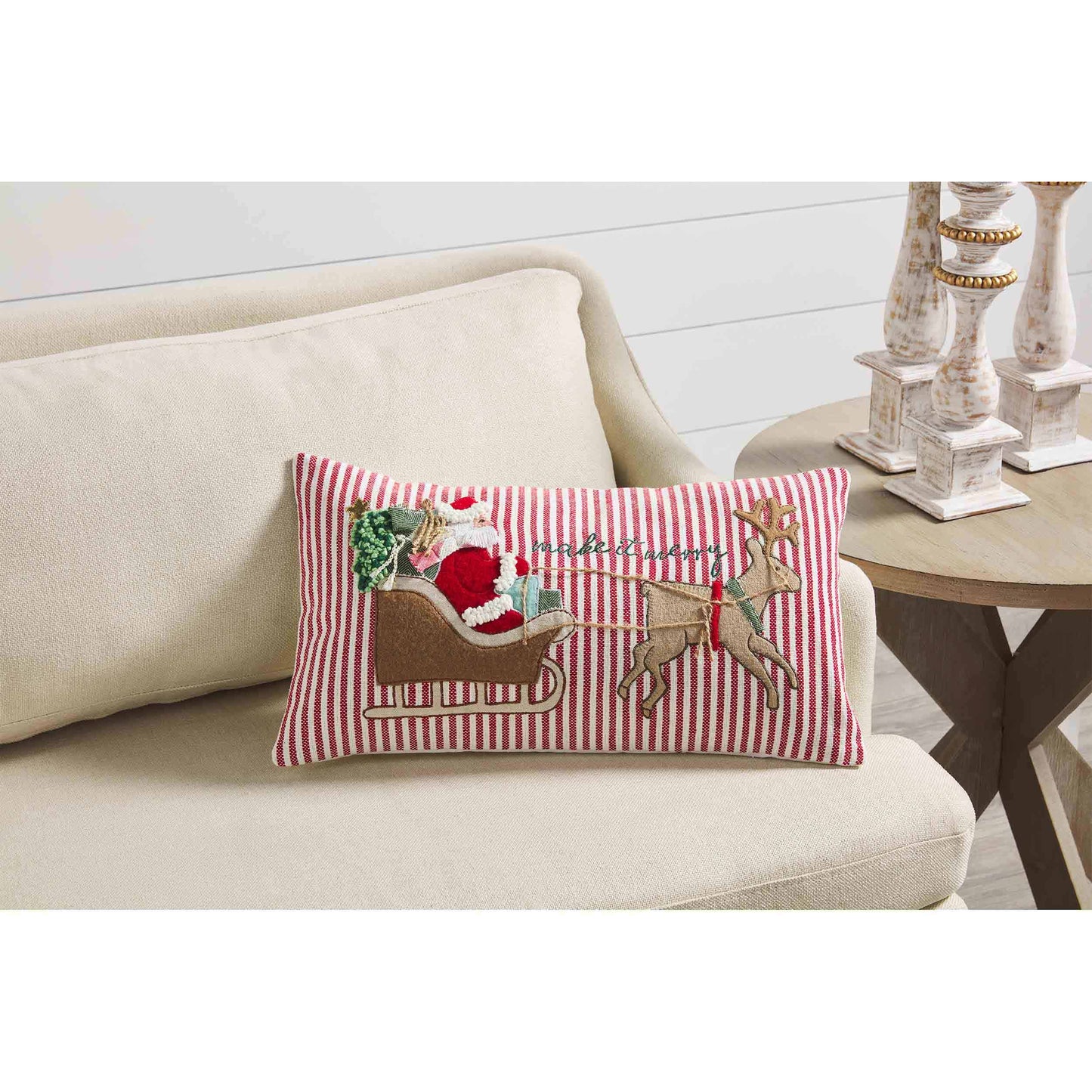 Make It Merry Sleigh Pillow set on an off-white couch.