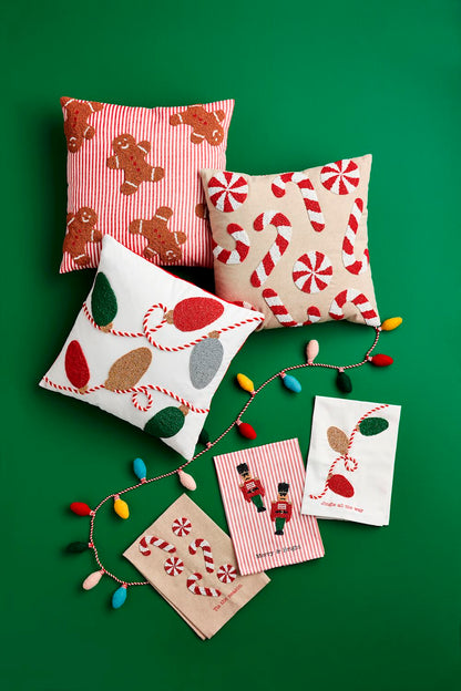 3 assorted Beaded Christmas Pillows arranged on a green background with christmas lights and towels.