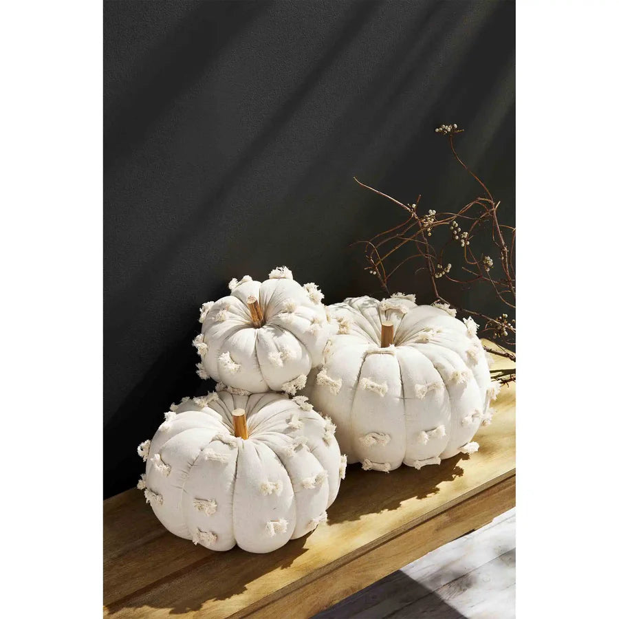 3 sizes of off white  cloth pumpkins arranged on a wooden bench.