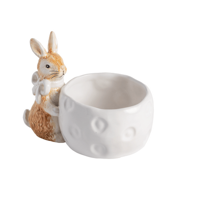 white ceramic bowl with brown ceramic bunny wearing white bow around its neck attached to the the side of bowl