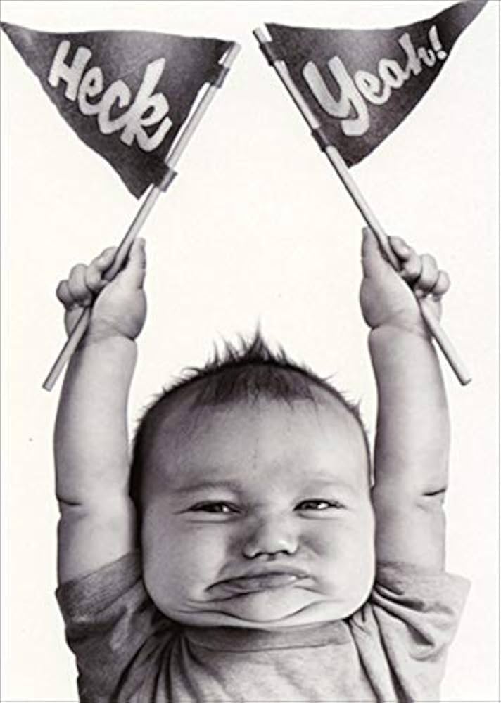 front of card is a baby holding up two pendant flags that say heck yeah in black and white