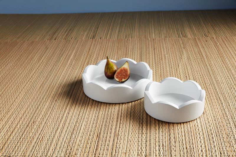Two sizes of round white trays set on a rattan surface.