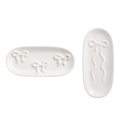 Two white ceramic trays with bow designs on a white background