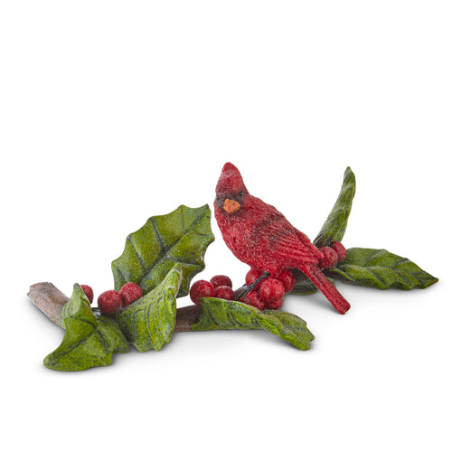 cardinal bird standing on a holly branch against a white background