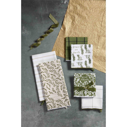 all three styles of white and green christmas towel sets displayed on a dark gray surface next to green velvet ribbon and craft paper