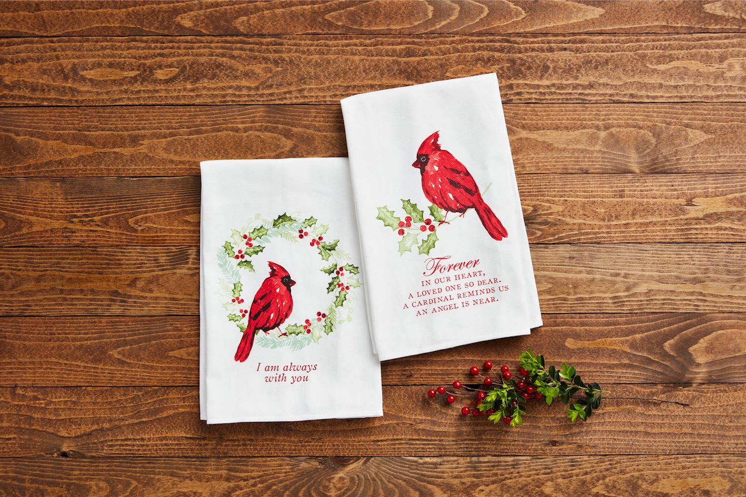 2 styles of cardinal towels arranged on a wooden background with a sprig of greenery.