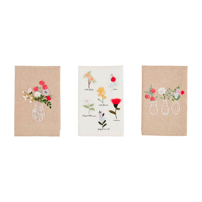 Three embroidered towels with floral designs on a white background