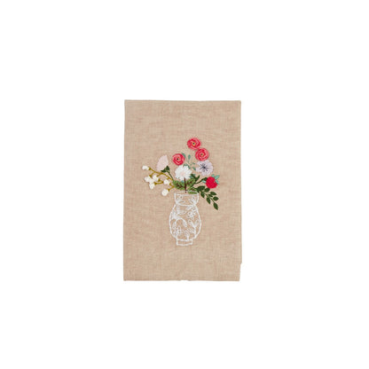 Beige towel with embroidered design of a vase with flowers shown on a white background