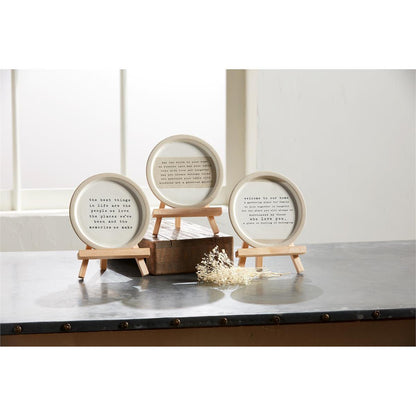 3 styles of sentiment plates on easels arranged on a countertop with dried flowers.