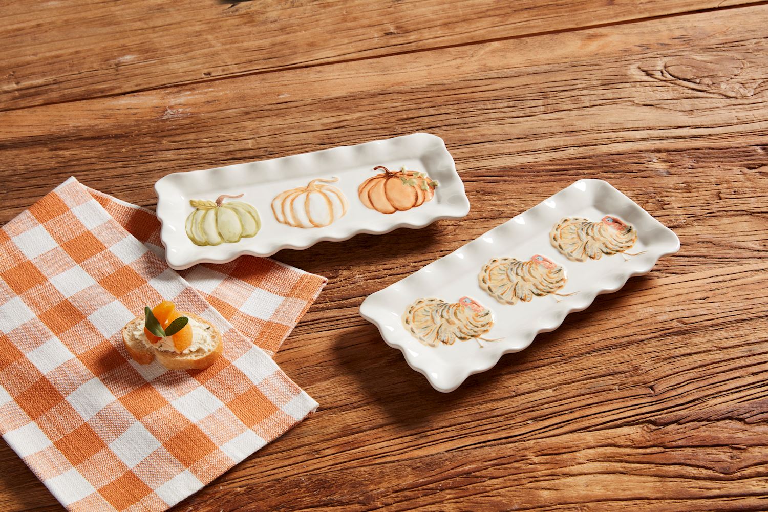 2 styles of little trays arranged on a table the an orange check hand towel and a snack.