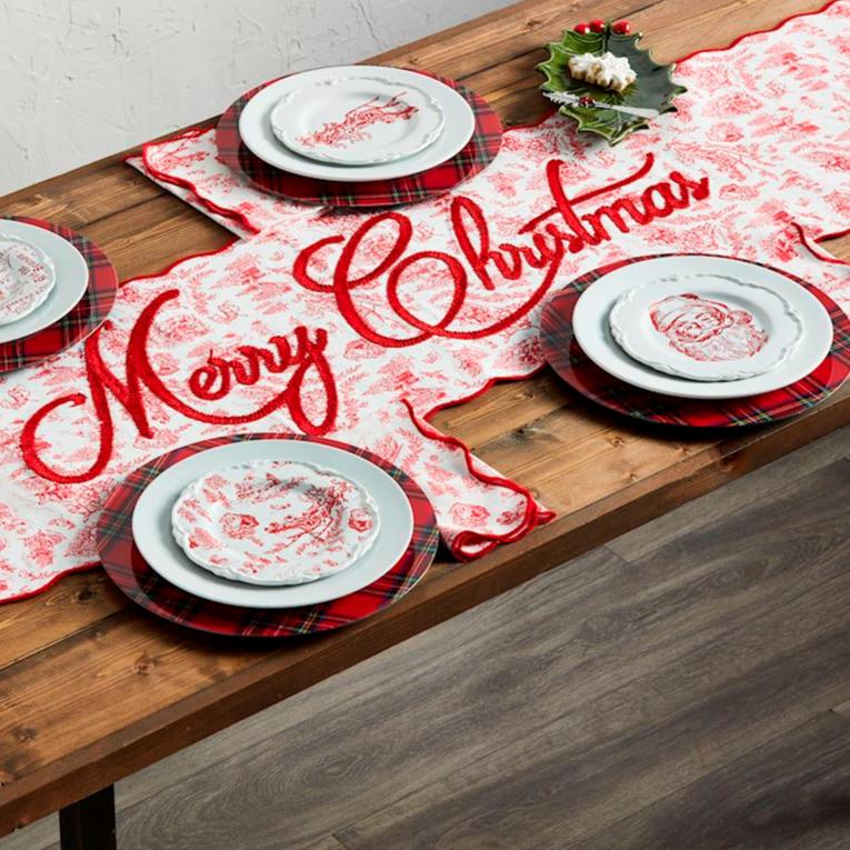 table top set with christmas runner, tartan chargers, and white and red dishes.