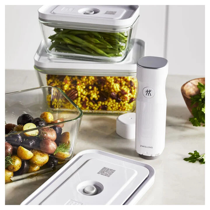 vacuum storage containers filled with foods set on a counter with a vacuum pump.